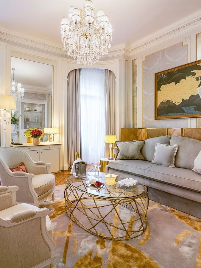 Lounge with a sofa placed by a glass table under a crystal chandelier in Prestige Suite at Hotel Westminster Paris