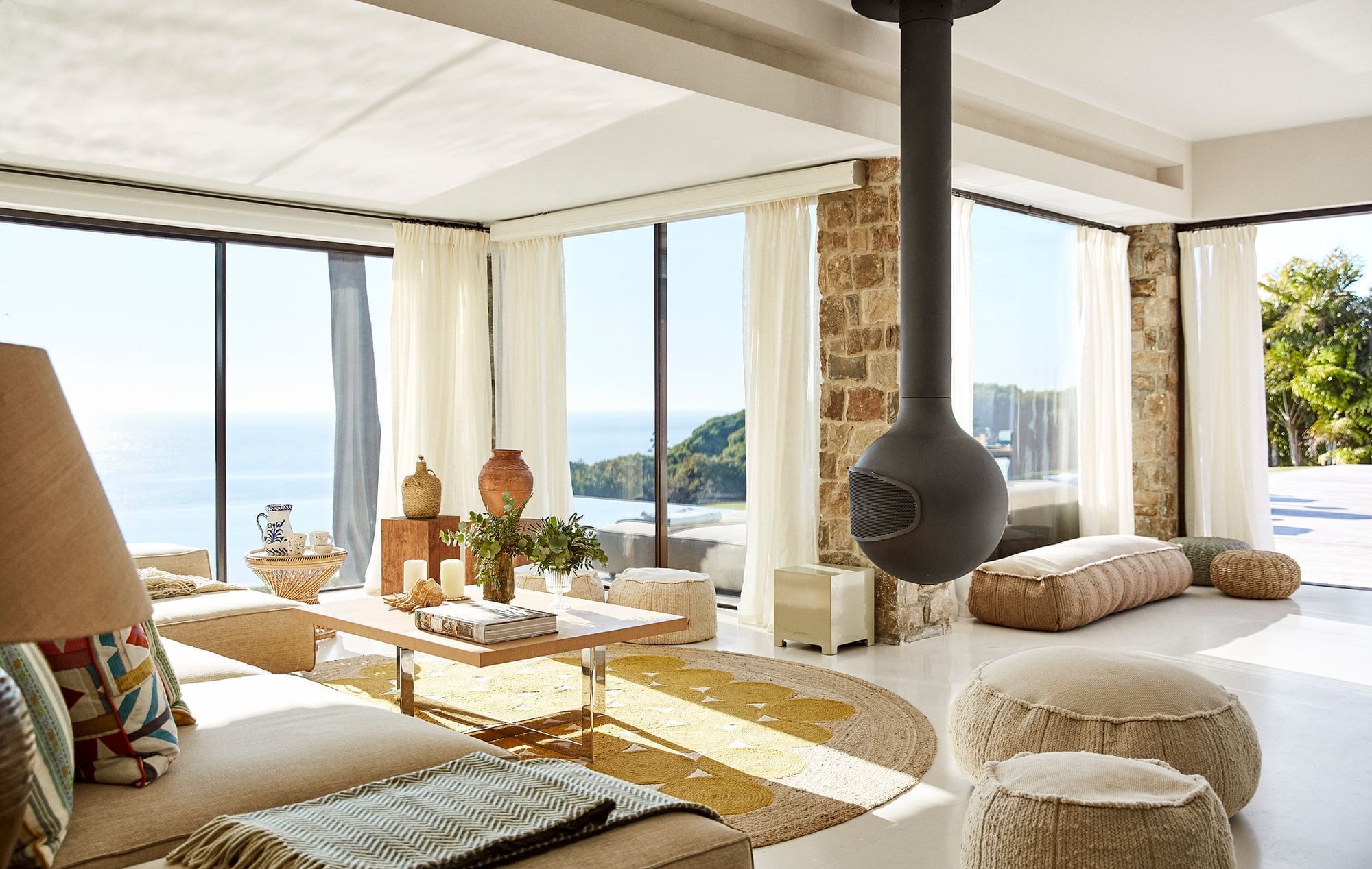 Bright, stylish villa living room with hanging fireplace and large windows overlooking the sea near Marbella Club