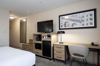 Standard Room with bed, TV, work desk and wall art at Sandman Hotel & Suites Winnipeg Airport