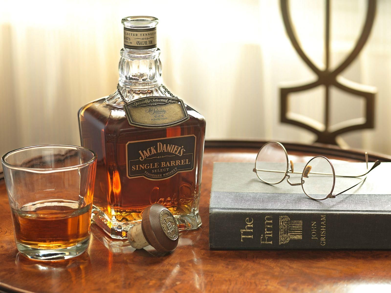 A bottle of Jack Daniel's with a whiskey glass and a book at Peabody Hotels & Resorts