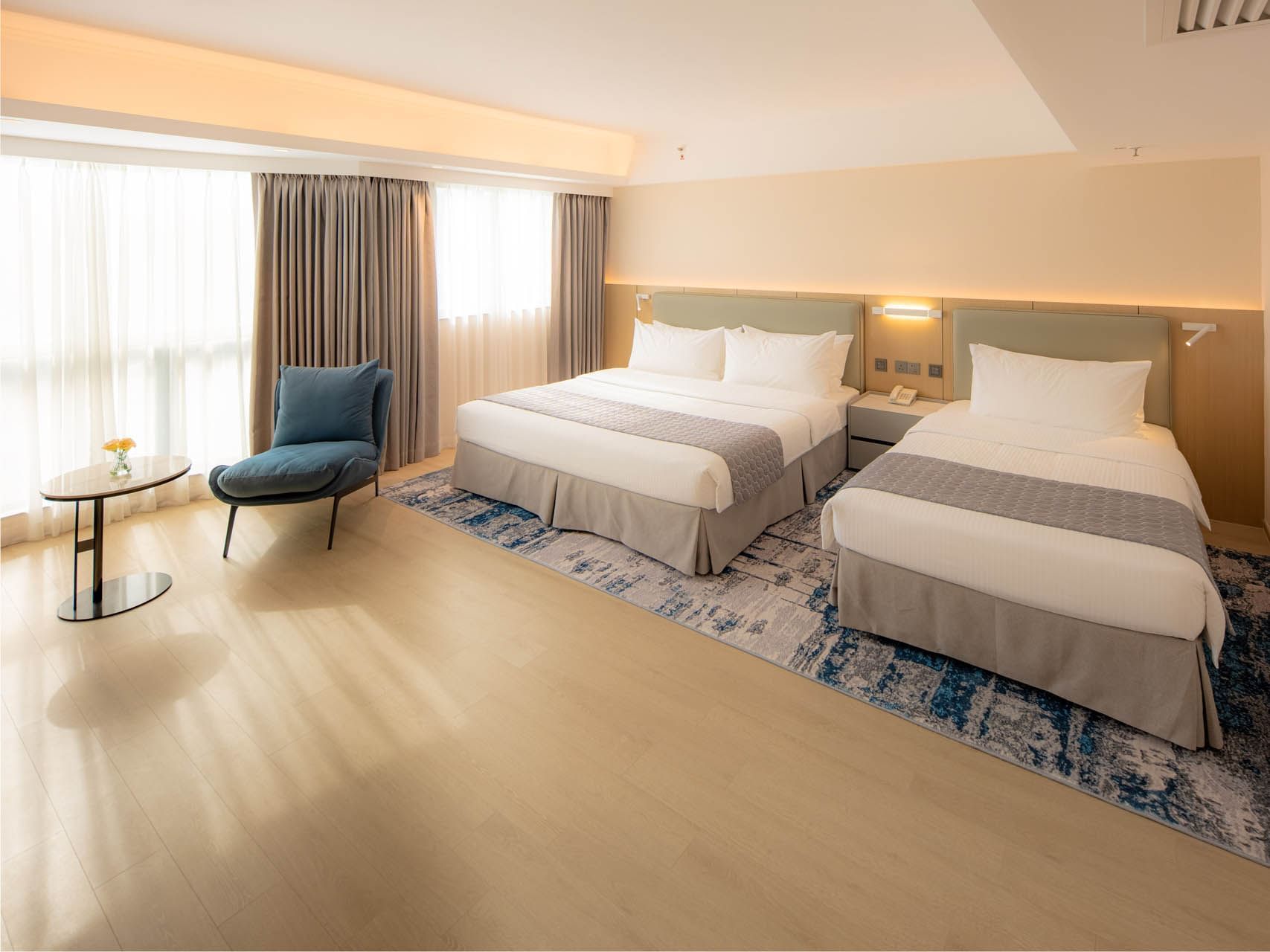 Cozy beds with blue decor and wood flooring in Family Room at Inn Hotel Macau, offering stylish hotel rooms in Macau