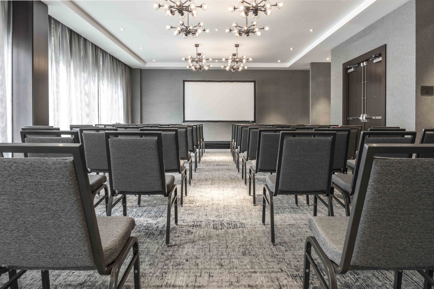Meeting space set theater style with projector screen 