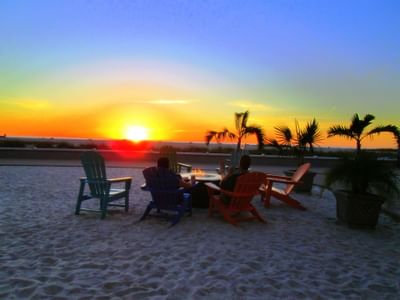 people sitting around a fire watching the sunset