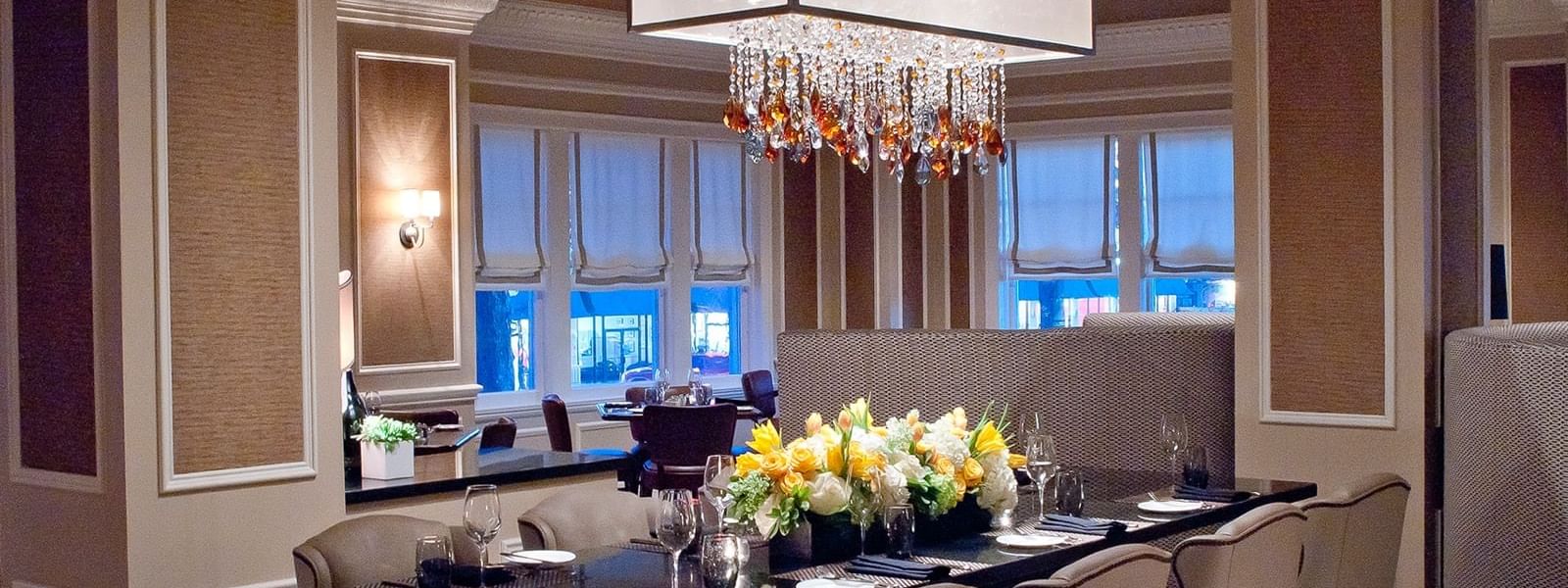 Long dining table with upholstered chairs under a glowing rectangular chandelier in The Land Mark at Warwick Melrose Dallas