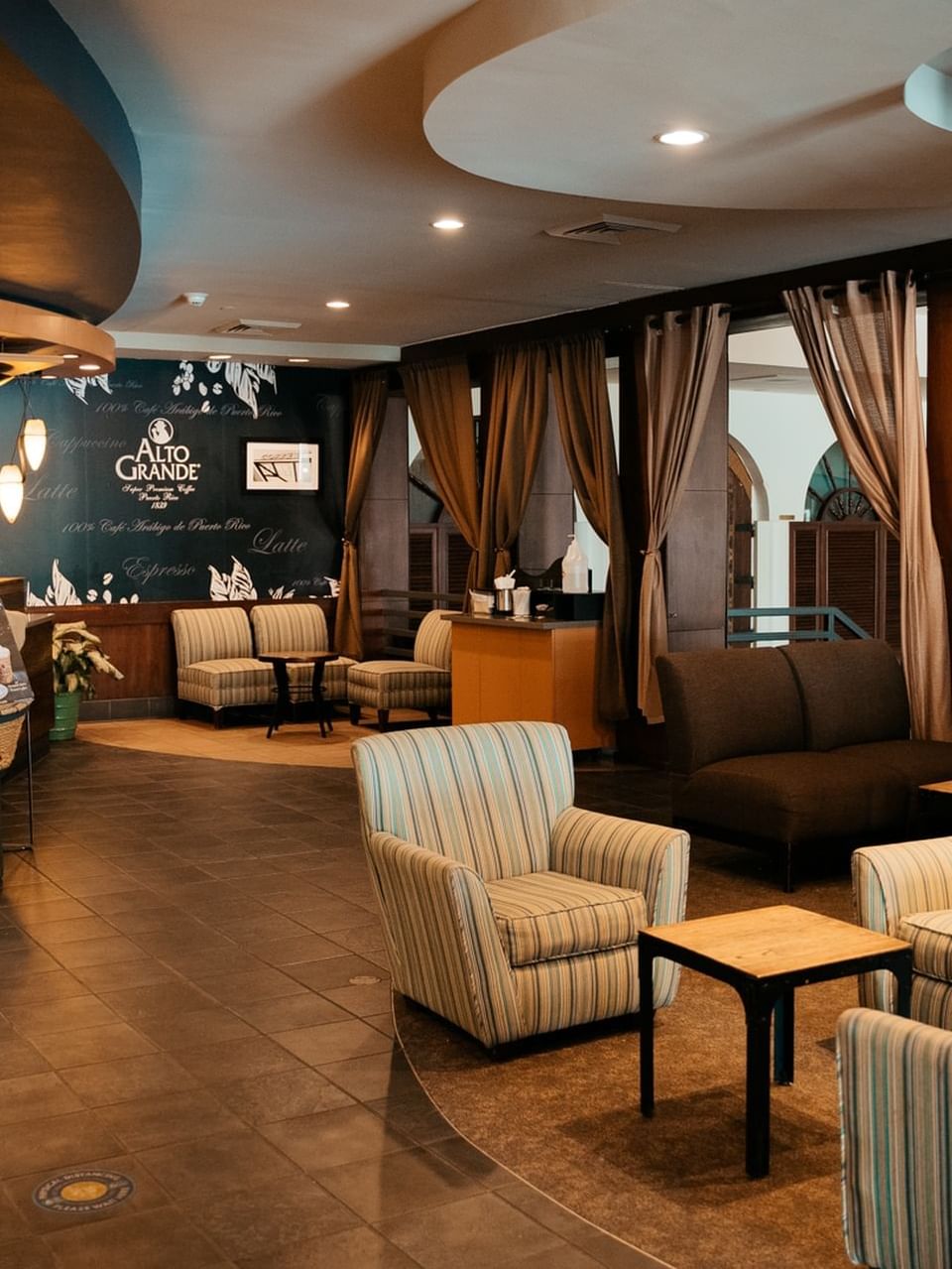 El Cafecito interior featuring striped chairs, a sleek counter, and elegant curtains at El Conquistador Resort