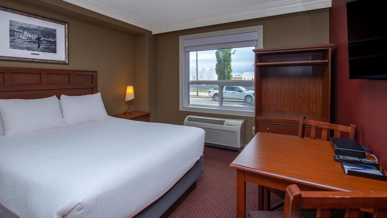 Guest room with white bedding, wooden furniture, and street view window at Coast Edson Hotel