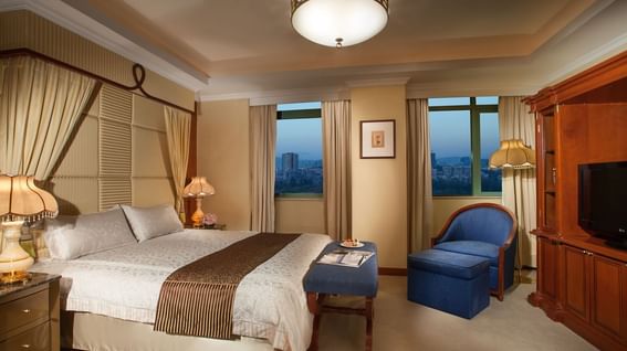 King-size bed by the window with a single sofa & a TV in a hotel room at Park Hotel Group