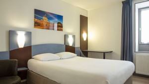 a bed with white bedding in a room at the Originals Hotels