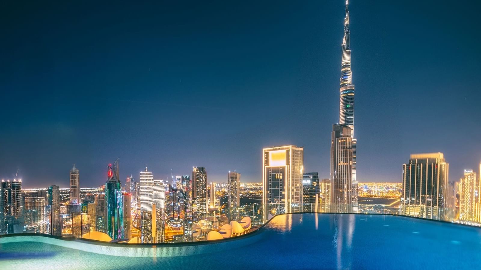 Relaxing rooftop infinity pool at Paramount Hotel Midtown, overlooking a stunning skyline and the Burj Khalifa