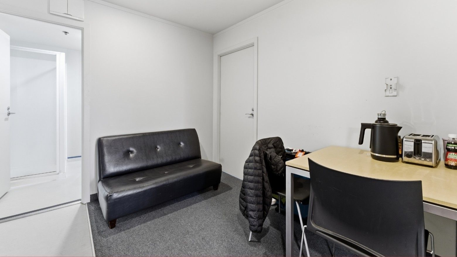 Black couch and table with black chairs and toaster in a room at UniLodge Stafford House.