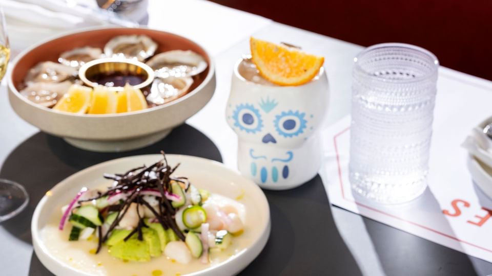 Table avec un bol d'huîtres, une salade et une boisson au restaurant de l'hôtel X