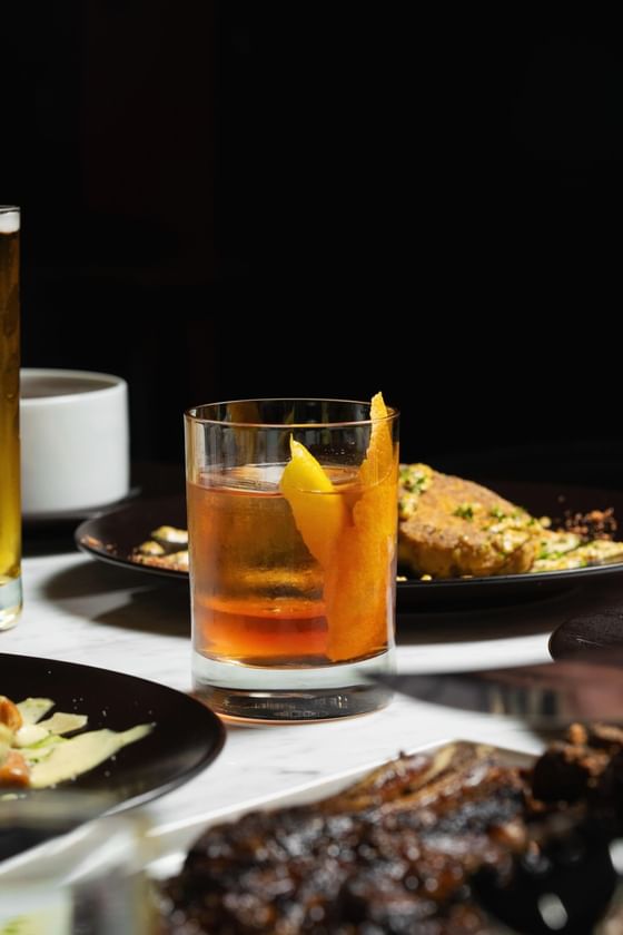 Rabo-de-galo cocktail with a plated meal in a dimly lit setting at Cypress & Oak, a steakhouse in Frankfort, KY