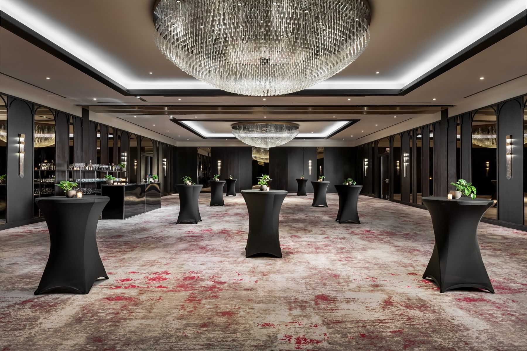 Princes\' Gates Ballroom with black cocktail tables set under a large crystal chandelier by a bar at the Hotel X Toronto