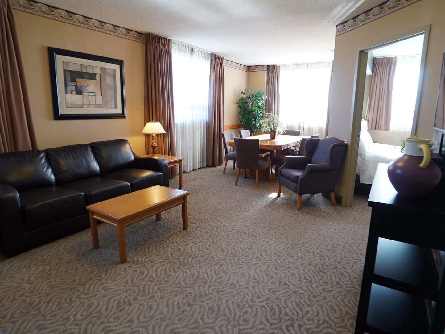 Living & dining areas with carpeted floors in Executive Suite at The Glenmore Inn & Convention Centre
