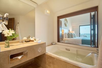 A contemporary resort bathroom design showcasing a luxury bathtub and ambient back-lit mirror.