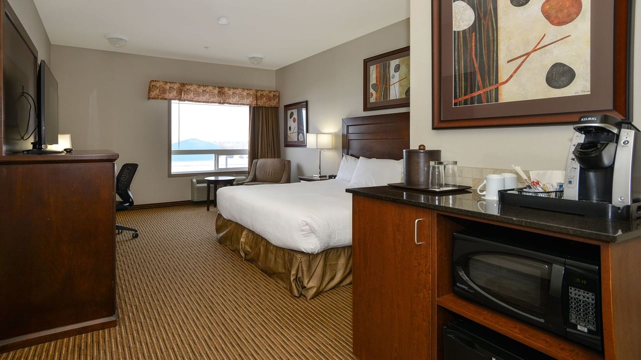 Hotel room with king bed, coffee machine, microwave, TV, work desk and window