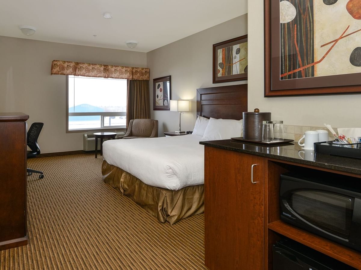 Hotel room with king bed, coffee machine, microwave, TV, work desk and window