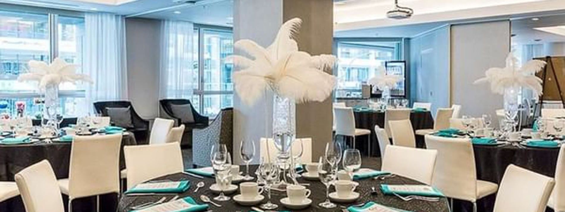 Dining tables with feather centerpieces and teal napkins in Ballroom at Warwick Le Crystal Montreal