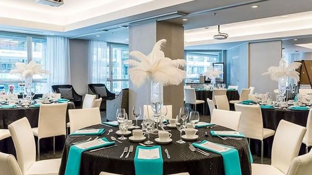 Dining tables with feather centerpieces and teal napkins in Ballroom at Warwick Le Crystal Montreal
