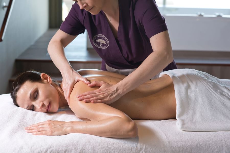 Professional therapist performs a relaxing back massage on a client in a spa at Le Grand Hôtel des Thermes