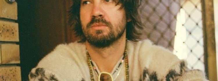 Tame Impala, wearing white sweater and beaded necklaces, for the Deadbeat Tour 2026.