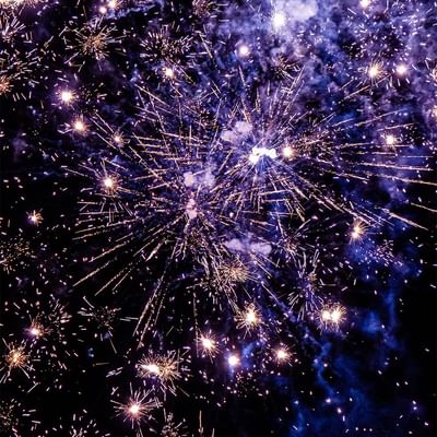 Funkelndes Feuerwerk am Nachthimmel mit strahlenden Lichteffekten und blauen Rauchschwaden.