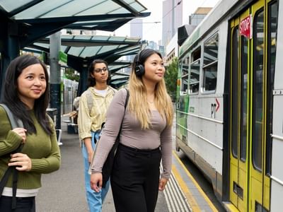 Three students waiting for the tram at Student Living 800 Swanston.