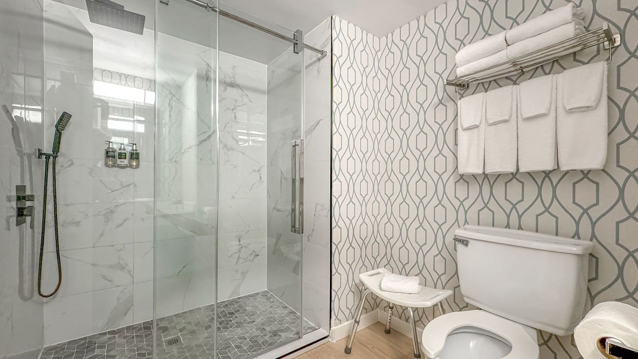 Accessible bathroom with toilet, sink, towels, and shower