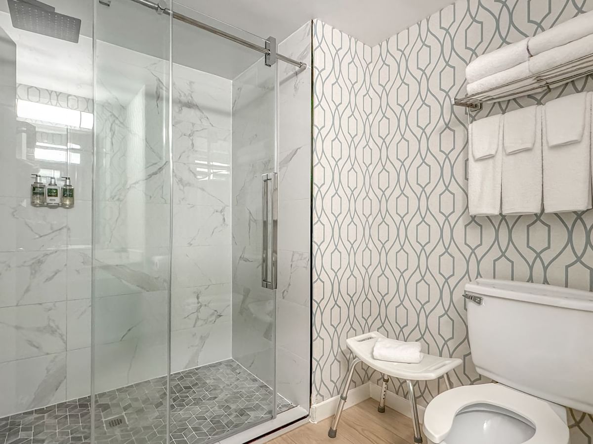 Accessible hotel bathroom with toilet, shower, towels and soap