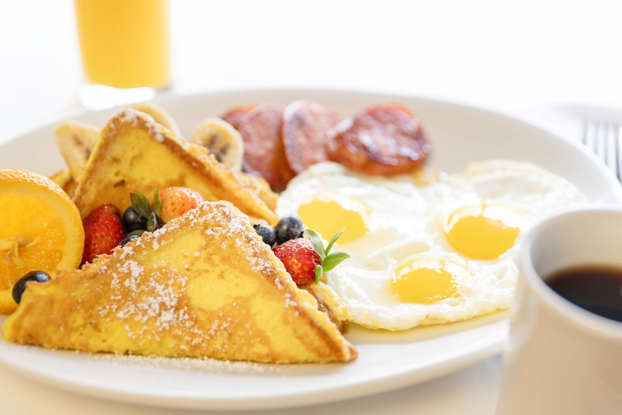 a plate of breakfast food with eggs, toast, fruit, and coffee