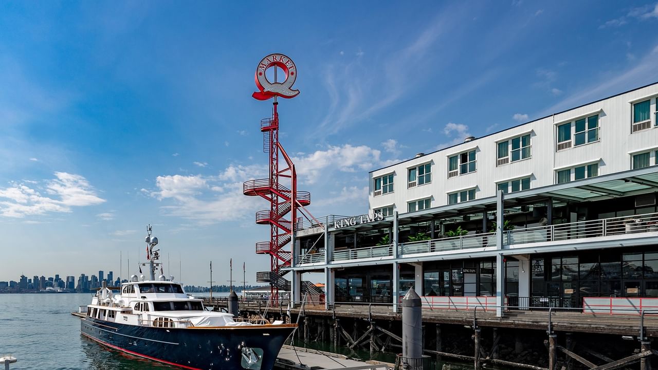 Coast Lonsdale Quay hotel exterior with a ship docked nearby and downtown Vancouver skyline