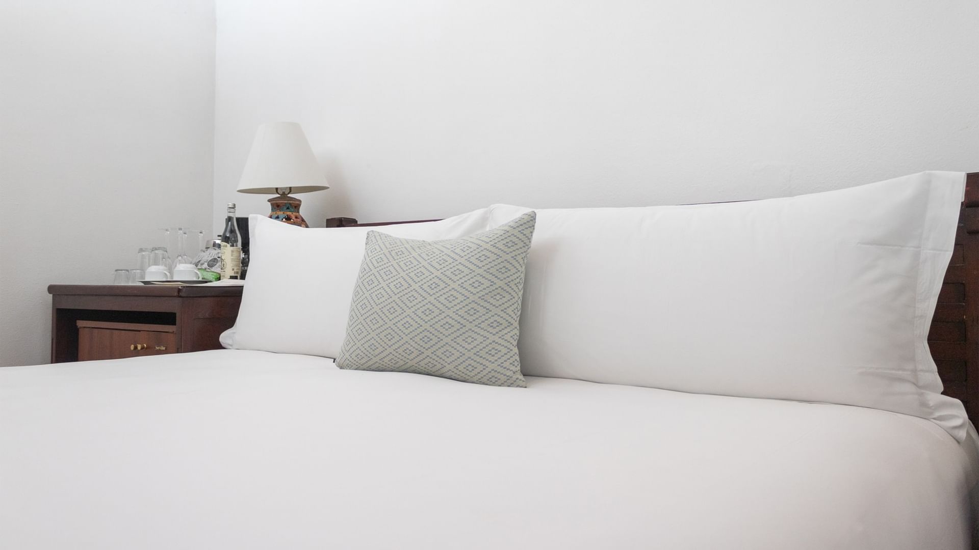 King bed with white linens and pillows in a neatly arranged room at Quinta Real Oaxaca in Oaxaca de Juarez.