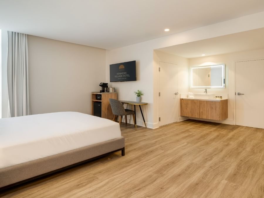 Spacious accessible bedroom with queen bed, wood-style flooring, work desk, and vanity at Kenmore Village Hotel South Beach
