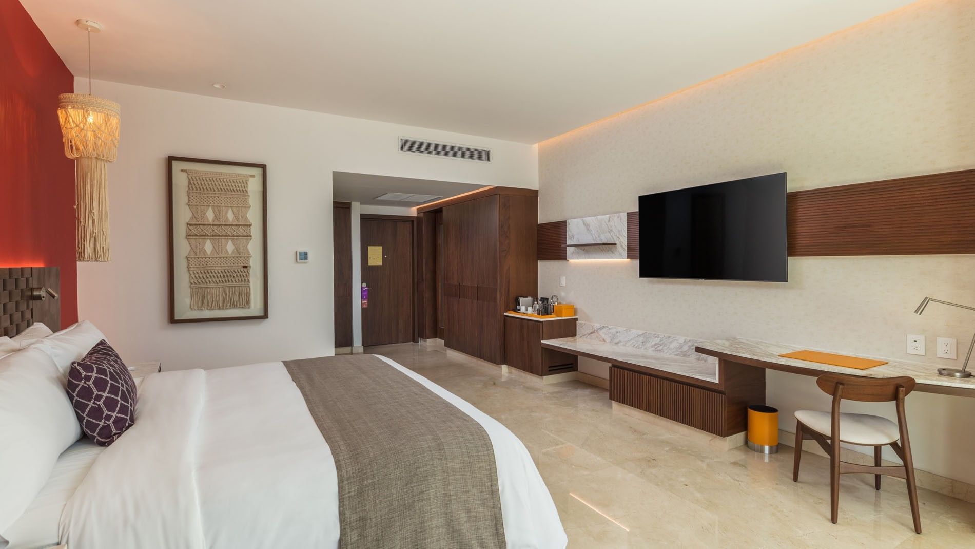 King Deluxe Superior interior showing a wall-mounted TV, marble desk, and warm wood storage cabinetry at Camino Real Merida
