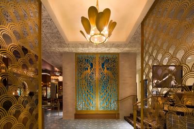 Art Deco style entrance with intricate golden and blue screens and a decorative chandelier at Hotel Bijou