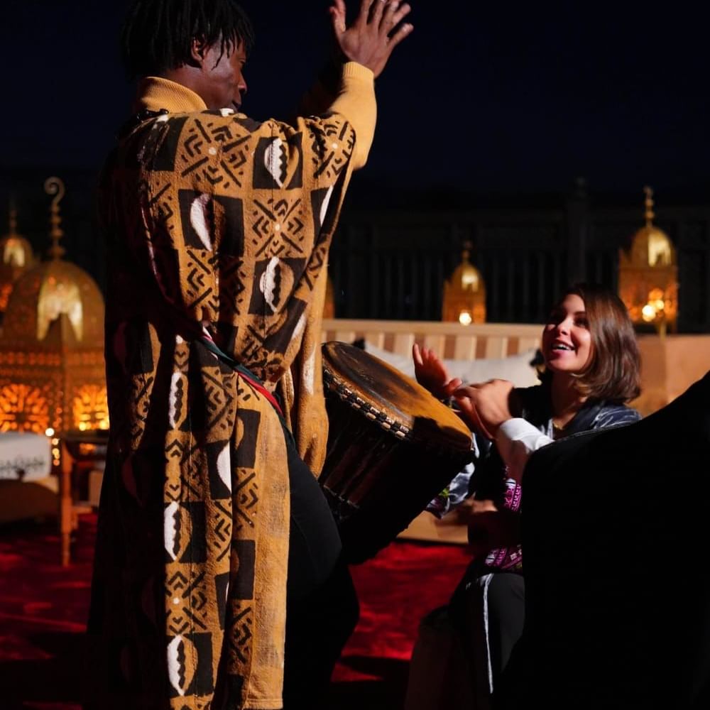A woman in a colorful oriental dress playing a drum on the rooftop at Selman Marrakech