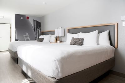 Premium King with two white beds by a shared bedside lamp under a large Chicago skyline mural wall at Hotel Saint Clair