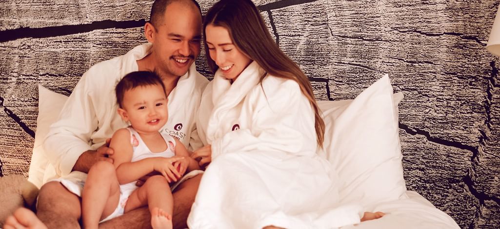 family of three cuddle on the bed