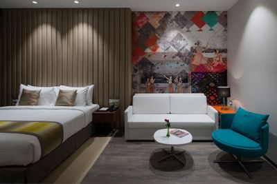 Bed by the sofa & table in Studio King Room at Eastin Residences Vadodara