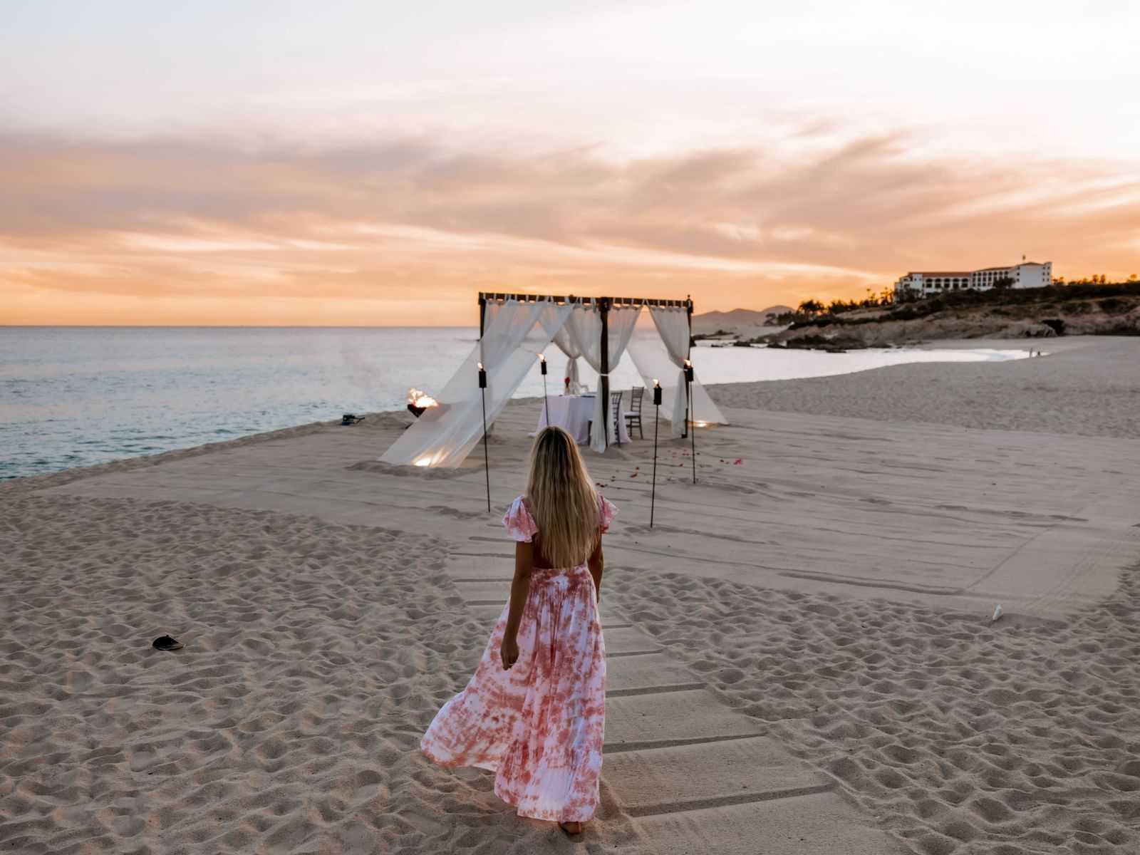 Girl walking towards a dinner setup at the beach in Los Cabos