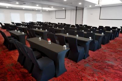 Red Room with two project screens, tables and chairs in one of the event space in San Jose Costa Rica at D Sabana Hotel
