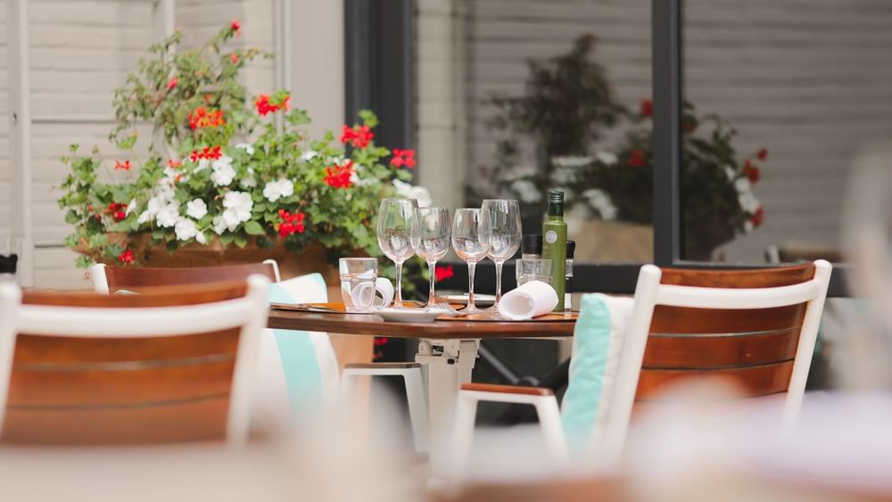 Elegant outdoor table with wine glasses and red flowers at Hotel Barsey by Warwick