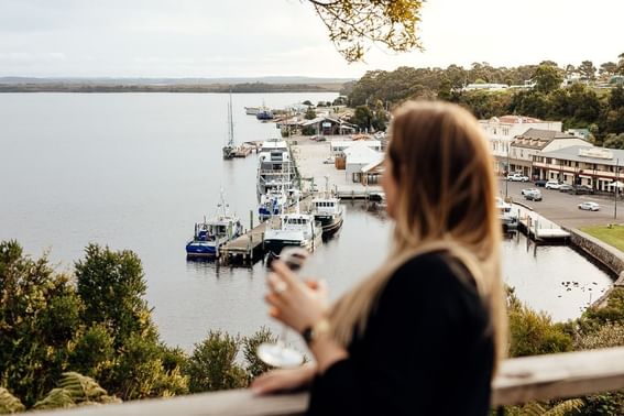 Lady having a champagne and enjoying a scenic view near Strahan Village