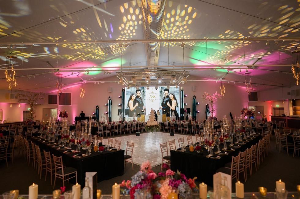 The King Suite set for a large wedding reception with a dance floor, video wall and colourful lighting