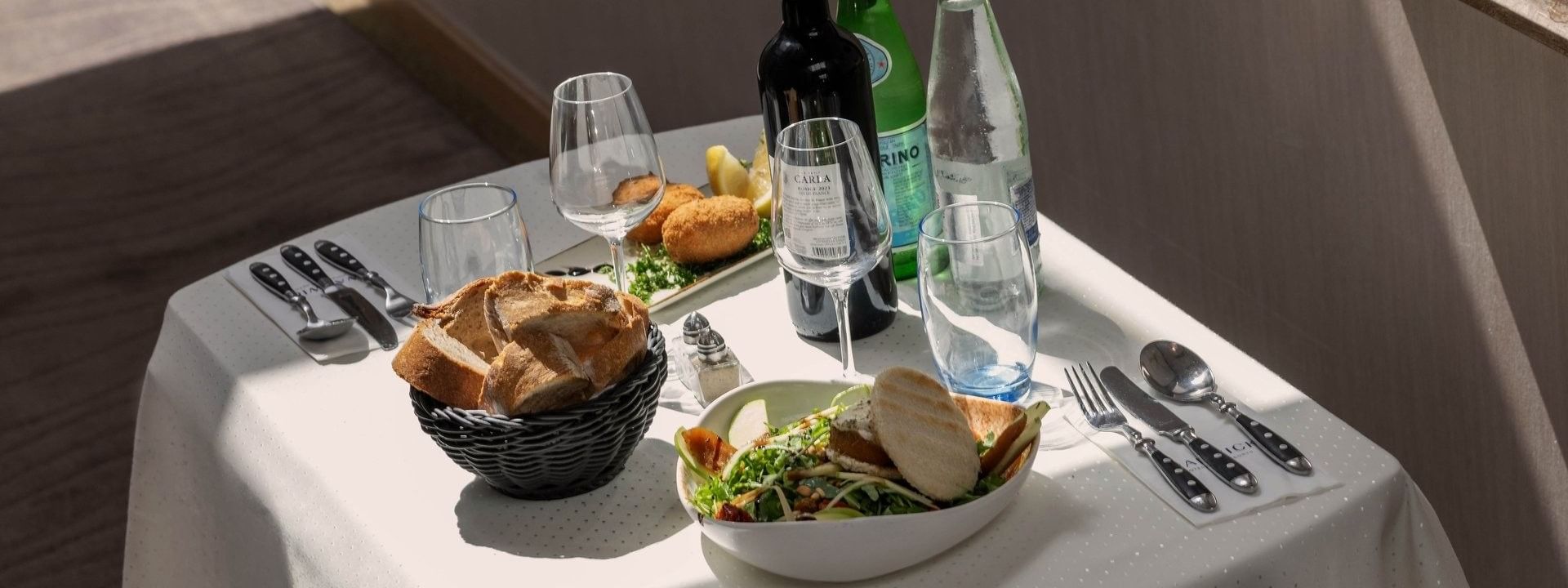 Table setting for one with bread in a basket placed by a salad near wine bottles at Warwick Grand Place Brussels