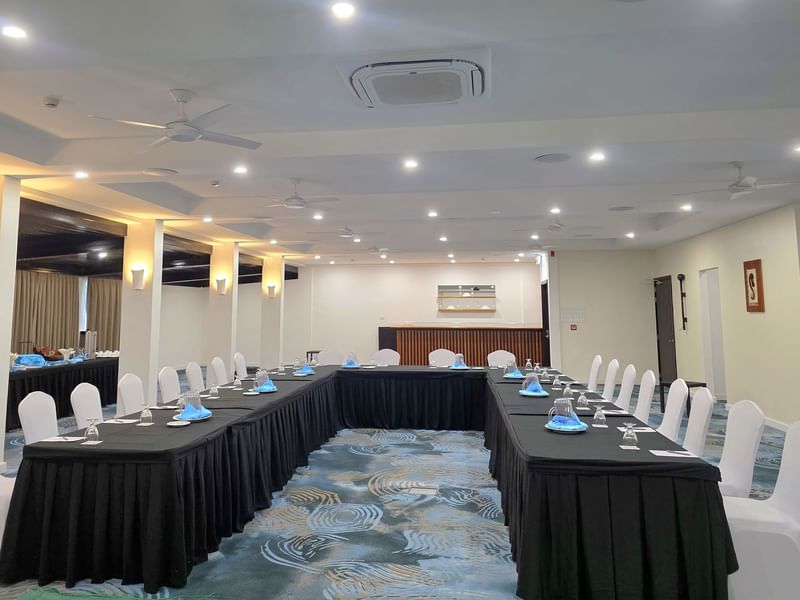 An empty conference room with tables and chairs, ceiling fans, and a projector on the ceiling at Warwick Hotels and Resorts