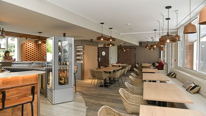 Restaurant élégant avec tables en bois et chaises en osier à Hôtel Rivella.