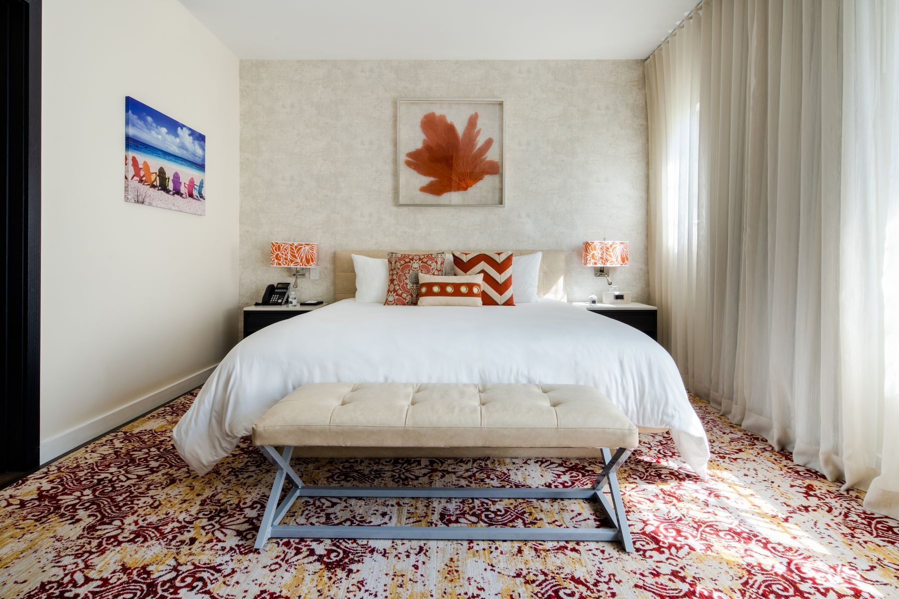 A wide view of a hotel room with a large bed, bench, and nightstands.