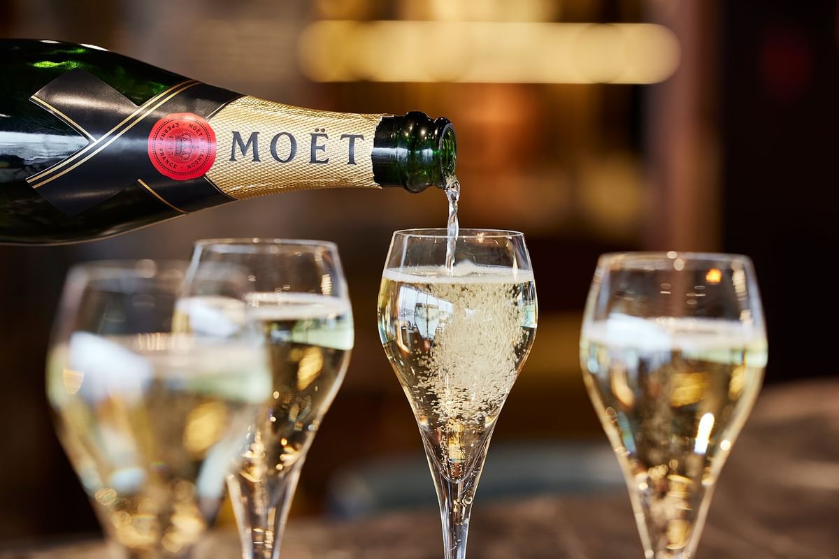 Champagne från Moët hälls i ett av tre glas med bubblande vätska, ett glas är tomt.