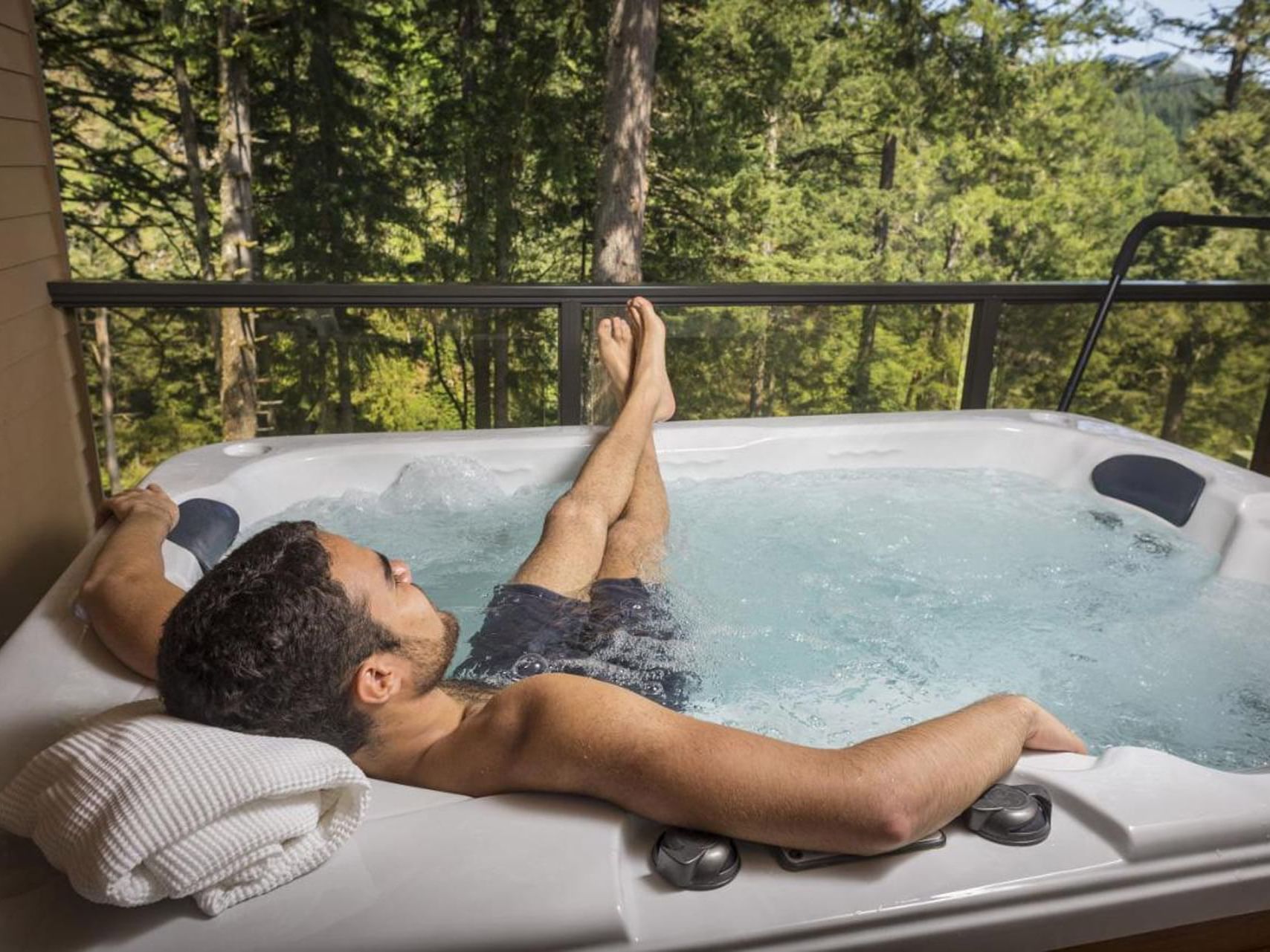 Man relaxing in hot tub next to a balcony at Carson Hot Springs